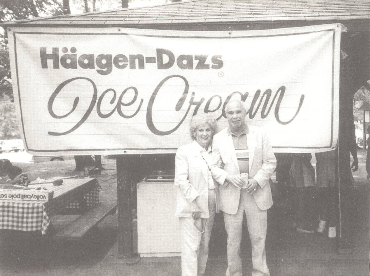 Rose Mattus and her husband, Reuben Mattus, standing in front of a sign "Häagen-Dazs Ice Cream"