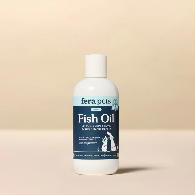 A white bottle of Fera Pets Liquid Fish Oil, with a blue label that states "Supports Skin & Coat, Joints + Heart Health." The label features a cartoon illustration of a dog and a cat.